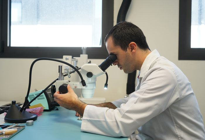 engineer looking at an electronic card through a microscope